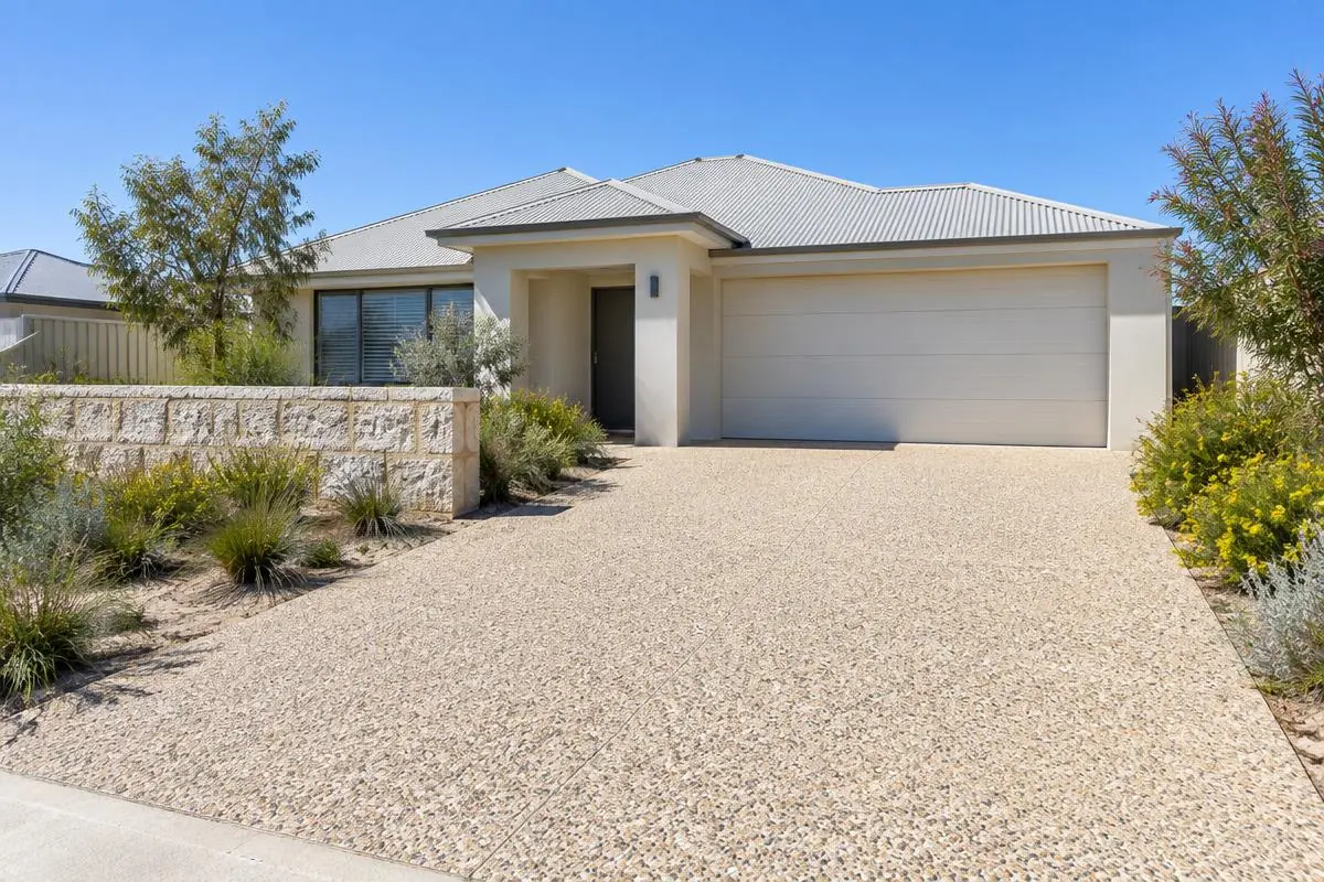 Illustrative image: exposed aggregate driveway at a rendered Perth home with a limestone garden wall