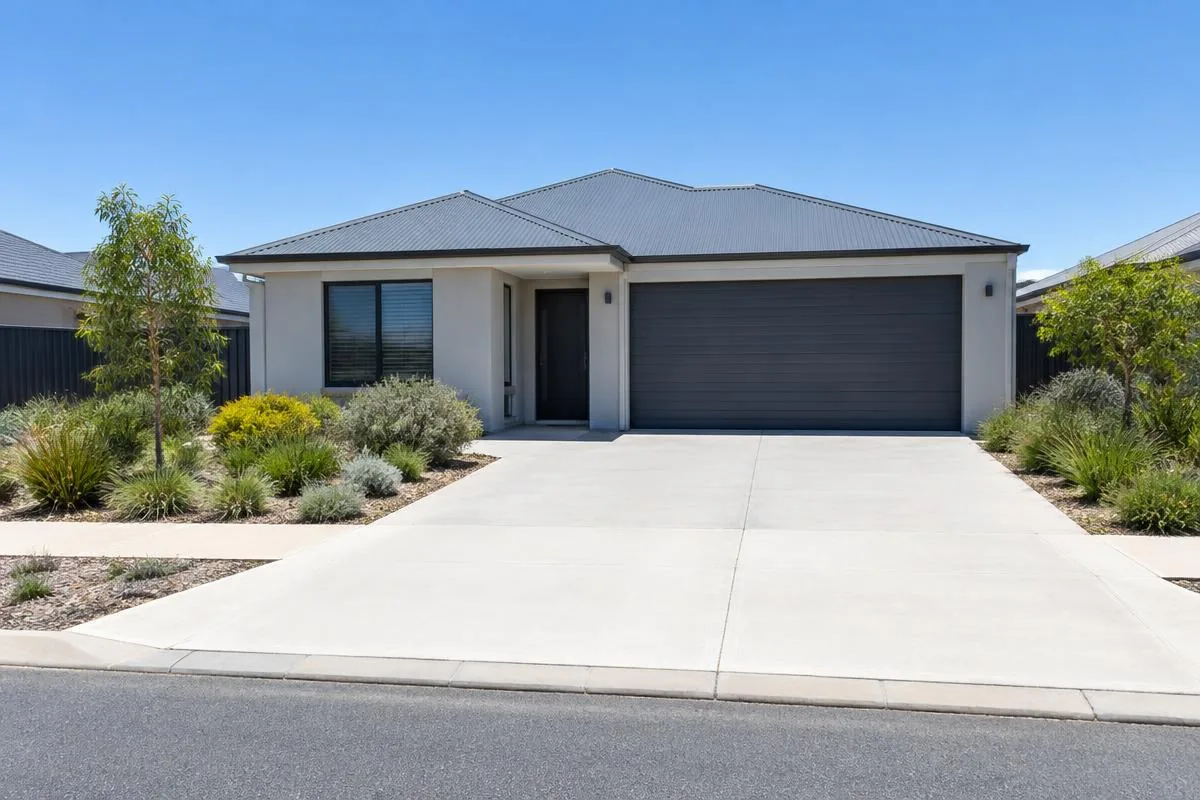 Illustrative image: wide concrete driveway at a rendered Perth home continuing across a concrete verge crossover to the kerb
